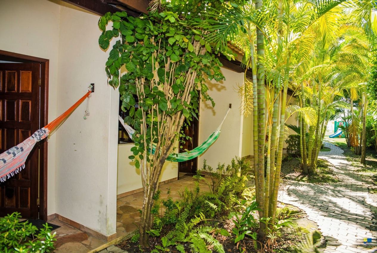 Área dos apartamentos com redes, jardim tropical e caminho de pedras